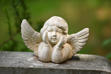 A little white angel with spread wings on a tombstone.