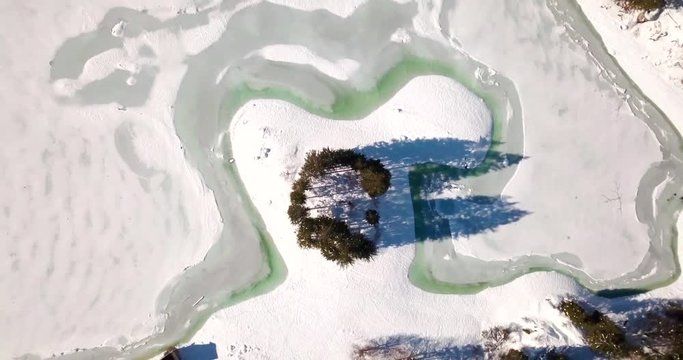Lago del Predil, Tarvisio / Italy a frozen alpine lake in a snow-covered winter fairytale mountain landscape. People Ice skating on a frozen lake in Italy