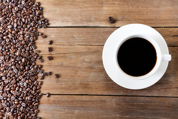 Fresh coffee with fragrant aroma in a white cup and coffee beans on an old wooden table. Top view - image