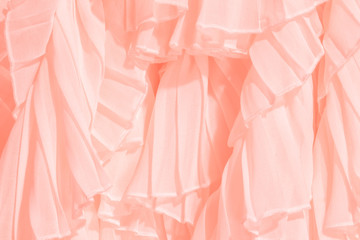 Soft pastel color chiffon fabric folds. Coral dress with ruffles and frills. Trendy color of the year.