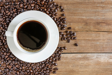 Fresh coffee with fragrant aroma in a white cup and coffee beans on an old wooden table. Top view - image