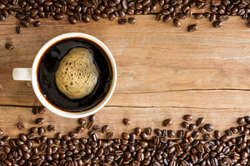 Fresh coffee with fragrant aroma in a white cup and coffee beans on an old wooden table. Top view - image