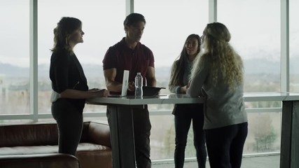 Tilt up to business people talking near window in office lobby / Pleasant Grove, Utah, United States
