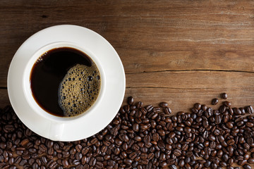 Fresh coffee with fragrant aroma in a white cup and coffee beans on an old wooden table. Top view - image