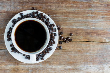 Fresh coffee with fragrant aroma in a white cup and coffee beans on an old wooden table. Top view - image