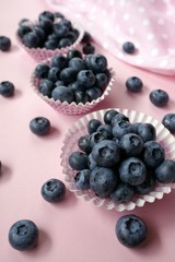 Blueberry berries. Blueberry muffins. Large blueberries in muffin tins and a pink towel on a light pink pastel background. Berry baking concept.