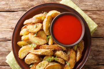 Hot potato wedges with parmesan cheese and oregano with pepper sauce close-up on a plate. horizontal top view