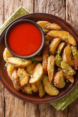 Delicious baked potato wedges with parmesan and oregano, served with pepper sauce close-up on a plate. Vertical top view