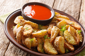 Fried potato wedges with parmesan and herbs with pepper sauce close-up on a plate. horizontal