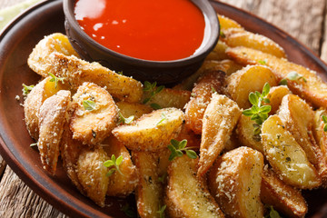Baked potato wedges with parmesan and oregano, served with pepper sauce close-up on a plate on the table. horizontal