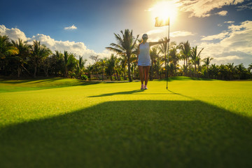 Young woman golfer standing on tropical golf course, sunset, Dominican Republic