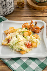 Healthy Grilled Caesar Salad with shrimp, parmesan Cheese and Croutons on wooden table