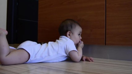 cute six months old teething baby boy puting clothes pegs in his mouth