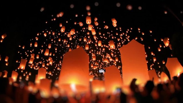 Time-lapse, Lanterns of light is released into the night sky by multi ethnic crowd. Celebrate lantern festival of light in Yeepeng festive at Chiangmai, Thailand. Low angle, wide shot, tilt-shift.