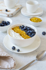 Bowl of greek yogurt, bee pollen and fresh berries on white stone background