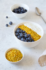 Bowl of greek yogurt, bee pollen and fresh berries on white stone background
