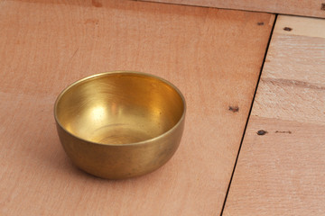 Ancient brass bowl for special ceremony on wooden table.