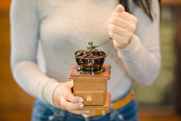 Barista grinding coffee by hand on a vintage coffee grinder