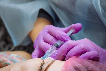 Beautiful young woman is getting a rejuvenating facial injections.  The beautician is filling...