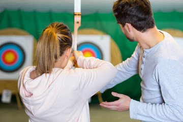rear view of woman aiming at archery target