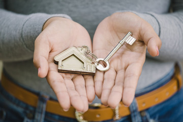 Female hand holding house key, real estate agent concept