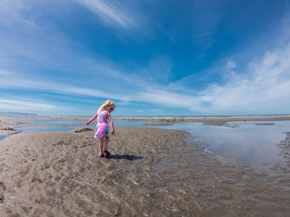 Girl wearing pink sunglasses at the beach pointing