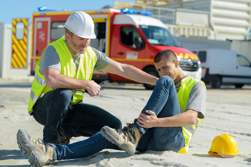 injured lying worker at work being assisted