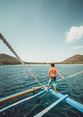 Naklejka premium Guy observing the view from a boat in a tropical island