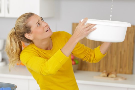 Woman Collecting Leaking Water In Bucket