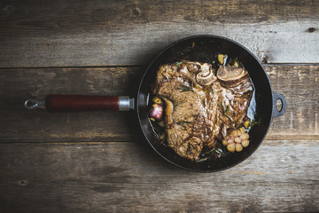 Grilled T-bone steak on the frying pan with garlic and rosemary. Selective focus. Shallow depth of...
