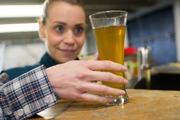 young smiling female brewery worker with bottling machinery on factory
