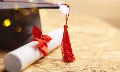 Graduation hat and diploma on wooden background - obrazy, fototapety, plakaty