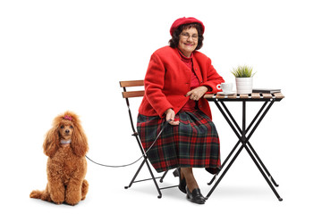Senior lady sitting in a cafe with a groomed red poodle