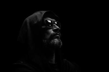 Fototapeta na wymiar Brutal man with grey beard in sunglass with hood on dark background.