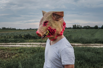 Unrecognizable man with a bloody pig mask. Horror scene