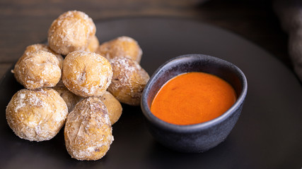 Famous Canary Islands dish, Papas Arrugadas (wrinkly potatoes with salt) and Mojo picon (red sauce) on wood table