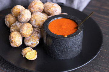Famous Canary Islands dish, Papas Arrugadas (wrinkly potatoes with salt) and Mojo picon (red sauce) on wood table - obrazy, fototapety, plakaty