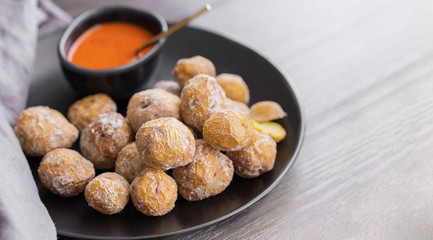 Famous Canary Islands dish, Papas Arrugadas (wrinkly potatoes with salt) and Mojo picon (red sauce) on wood table .Copy space