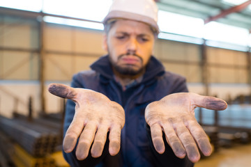 upset worker showing his dirty hands