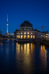 Fototapeta na wymiar Beautiful view of the illuminated Fernsehturm TV Tower, Bode Museum and its reflections on the Spree River in Berlin, Germany, at dusk.