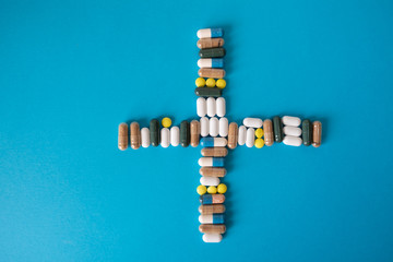 pill capsules folded in the shape of a cross on a blue background