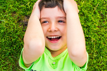 cheerful smiling boy lying on the grass in the summer