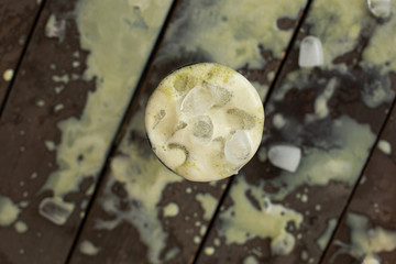 Ice cold sweet green lime tea drink on the wooden table with outdoor sun lighting with ice cubes and splashes of drink