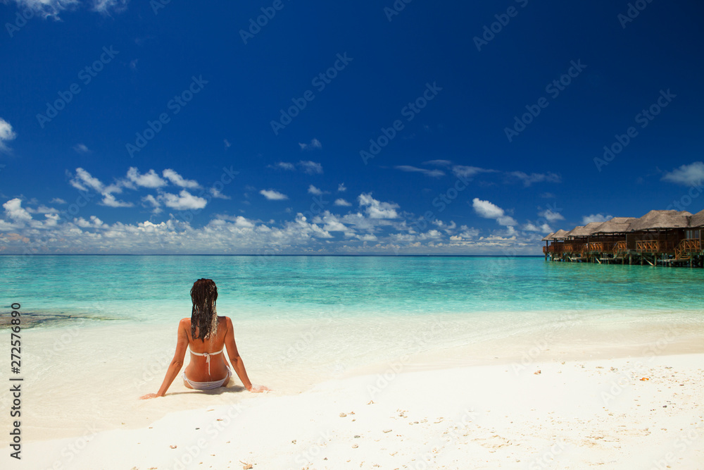 Wall mural Young fashion woman relax on the beach. Happy lifestyle. White sand, blue sky and crystal sea of tropical beach. Vacation at Paradise. Ocean beach relax, travel to islands