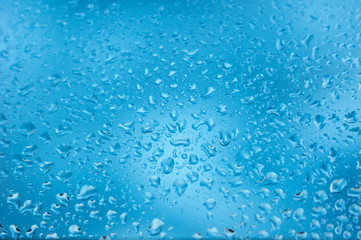viele kleine Wassertropfen auf einer Scheibe in blau bei Regen
