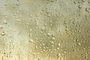 viele kleine Wassertropfen auf einer Scheibe in gold bei Regen