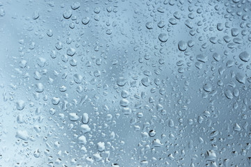 viele kleine Wassertropfen auf einer Scheibe in blau bei Regen