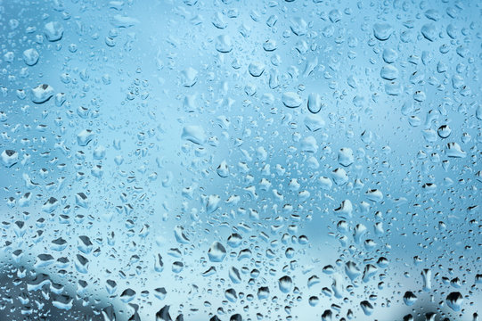 viele kleine Wassertropfen auf einer Scheibe in blau bei Regen