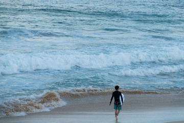 A surfer getting ready for the surf, going surfing in ocean