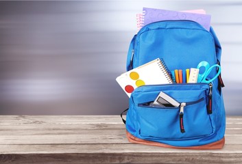 Colorful school supplies in backpack on white